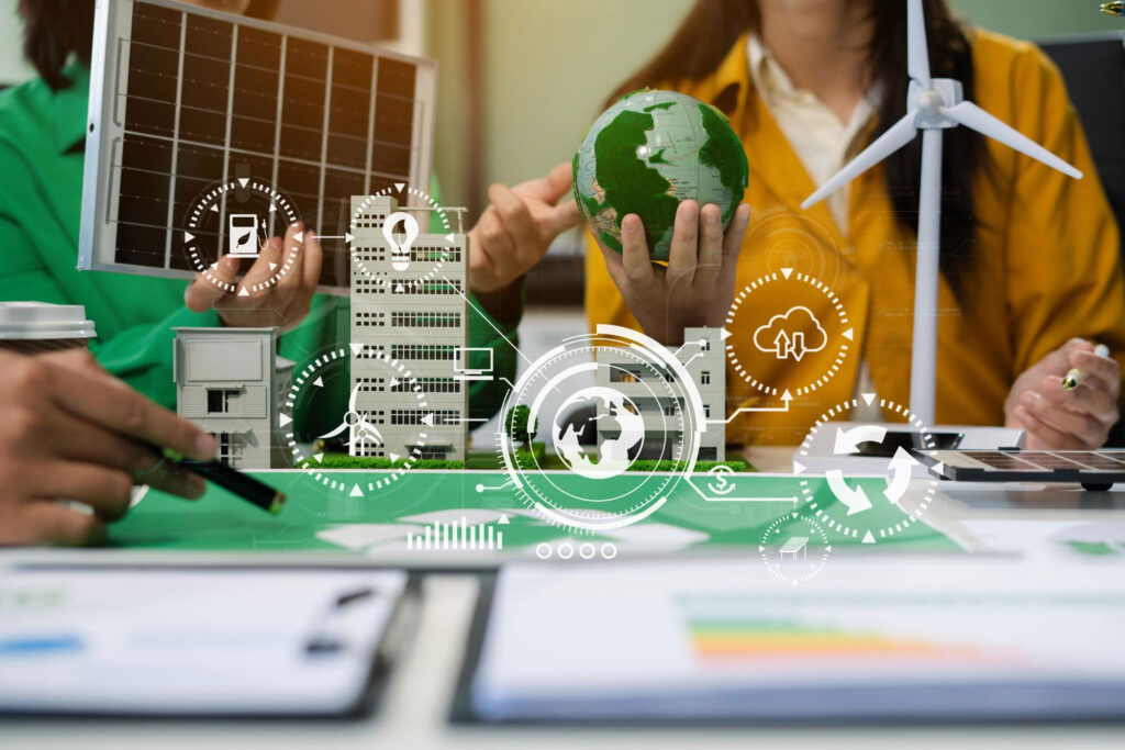 Equipo trabajando con modelos de edificios, paneles solares y aerogeneradores junto a iconos digitales de energía sostenible.